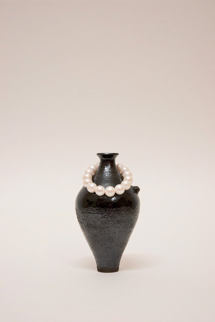 Artisanal handmade wheel-thrown ceramic vase tableware set. Dark Glaze ceramics. Hand built vessel with white pearl and silver bracelet.